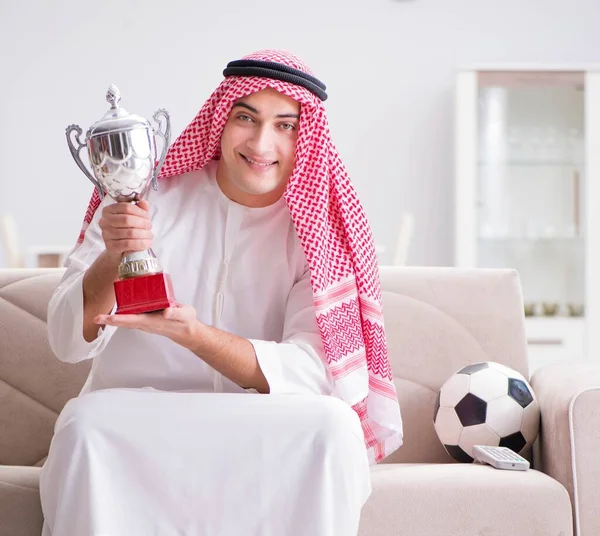 Hombre árabe joven viendo fútbol sentado en el sofá —  Fotos de Stock