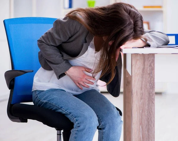 Mujer embarazada luchando con el dolor en la oficina — Foto de Stock