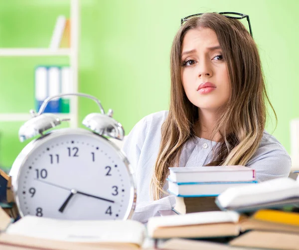 Jonge vrouwelijke student bereidt zich voor op examens met veel boeken in de tijd — Stockfoto