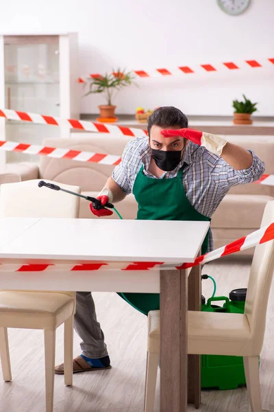 Young male sanitizer disinfecting indoors — Stock Photo, Image