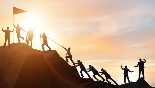 Concept of teamwork with team climbing mountain top — Stock Photo, Image