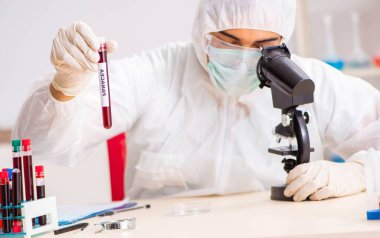 Genç yakışıklı laboratuvar asistanı hastanede kan örnekleri test ediyor.