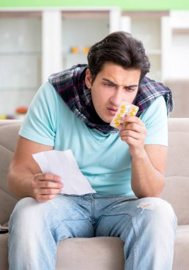 Evde hastalıktan muzdarip genç yakışıklı bir adam.