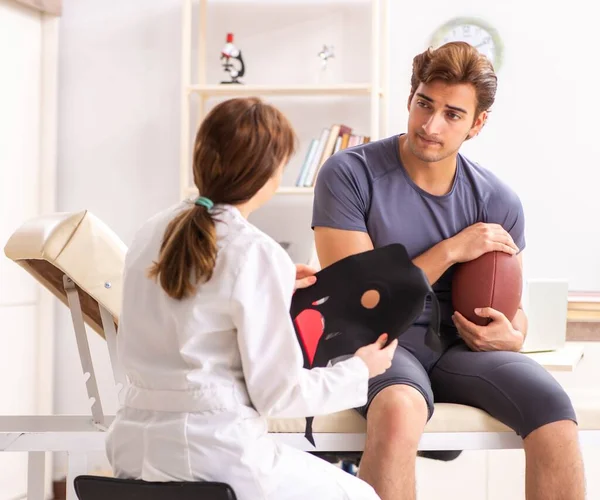 Bello giocatore di calcio americano in visita medico traumatizzato femminile — Foto Stock