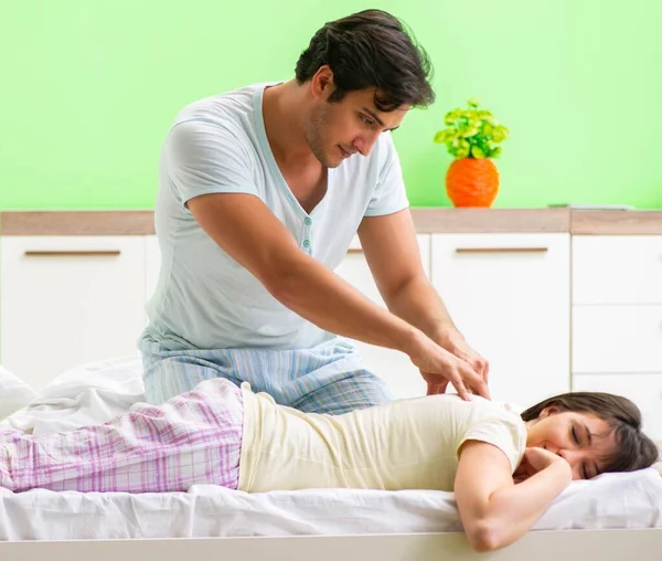 Man doing massage to his wife in bedroom — Stock Photo, Image