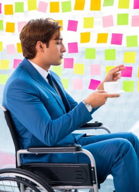 Birçok çelişkili önceliği olan tekerlekli sandalyedeki genç yakışıklı adam.