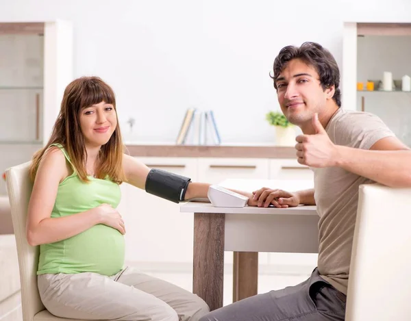 Echtgenoot controleert zwangere vrouwen bloeddruk — Stockfoto