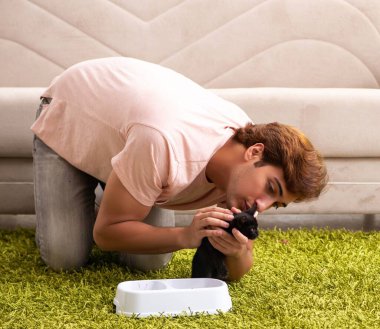 Genç adam evde kedi yavrusuyla oynuyor.