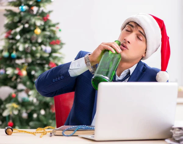 Young handsome employee celebrating Christmas at workplace
