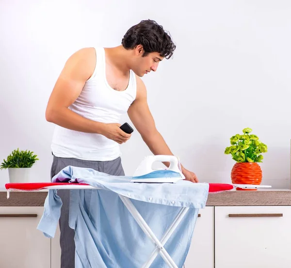 Hombre joven planchando en el dormitorio — Foto de Stock