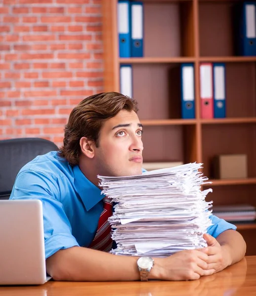Empleado joven con exceso de trabajo sentado en la oficina —  Fotos de Stock