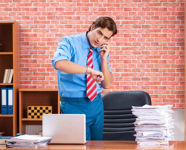 Jovem funcionário com excesso de trabalho sentado no escritório — Fotografia de Stock