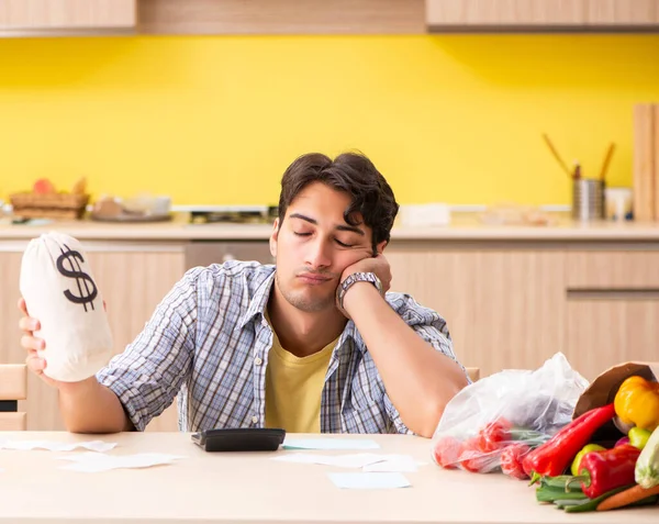 Jovem calculando despesas para legumes na cozinha — Fotografia de Stock