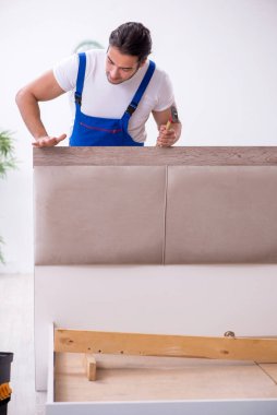 Genç erkek müteahhit eve mobilya kuruyor.