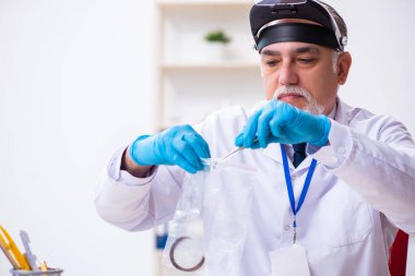 Kanıt için laboratuvarda çalışan yaşlı bir erkek kriminolog.