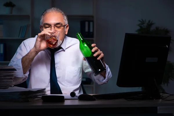 Old male employee working late in the office — Stock Photo, Image