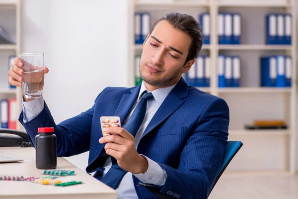 Jeune employé masculin et beaucoup de pilules sur le bureau — Photo