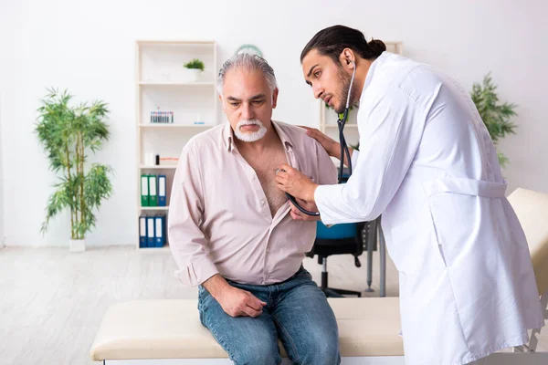 Oude man op bezoek bij jonge mannelijke arts cardioloog — Stockfoto