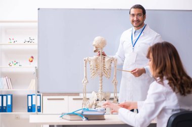 Genç erkek öğretmen doktor, iskelet ve kız öğrenci.