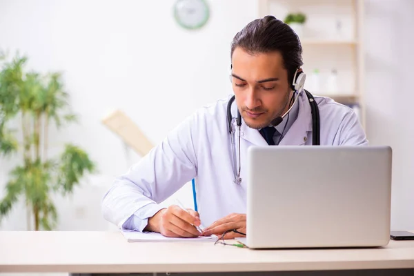 Junger Arzt hört Patient während telemedizinischer Sitzung zu — Stockfoto