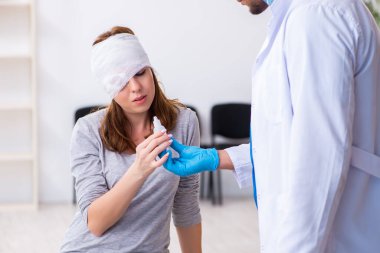 Genç baş yaralı kadın genç erkek doktoru ziyaret ediyor.