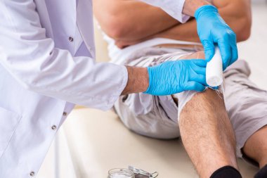 Yaralı adam ilk yardım konseptinde yaşlı doktoru ziyaret ediyor.