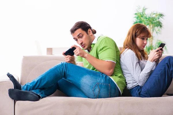 Young couple in gadget dependency concept — Stock Photo, Image