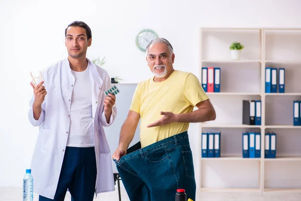 Doctor dietician and happy patient wearing large trousers — 图库照片