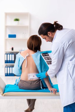 Yaralı genç kadın genç erkek doktoru ziyaret ediyor.