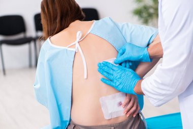 Yaralı genç kadın genç erkek doktoru ziyaret ediyor.