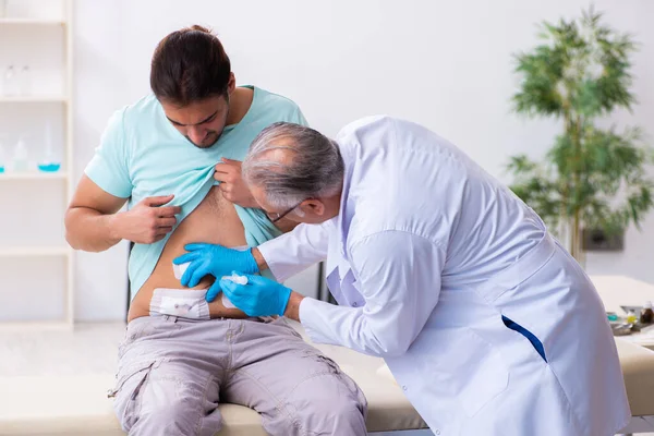 Injured young man visiting experienced male doctor — Stockfoto