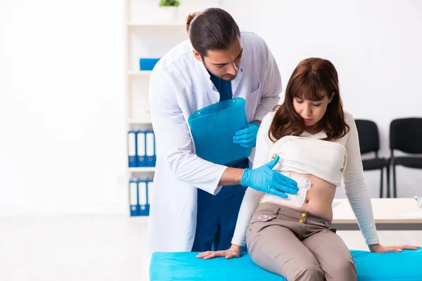 Mujer joven lesionada visitando al joven médico masculino —  Fotos de Stock