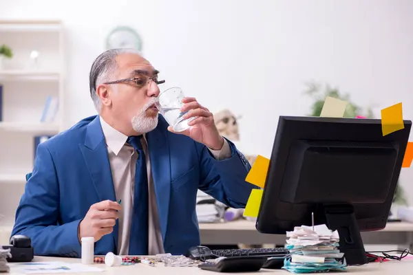 Ofiste fazla mesai yapan yaşlı bir erkek hasta. — Stok fotoğraf