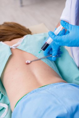 Genç sırtı yaralı kadın, erkek doktor masörünü ziyaret ediyor.