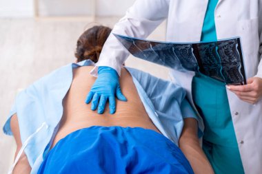 Genç sırtı yaralı bir adam, kadın doktor masörünü ziyaret ediyor.