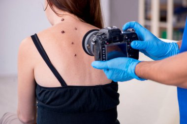 Genç bir kadın erkek doktor dermatoloğunu ziyaret ediyor.