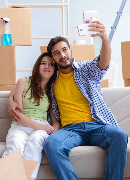 A jovem família desempacotando em nova casa com caixas — Fotografia de Stock