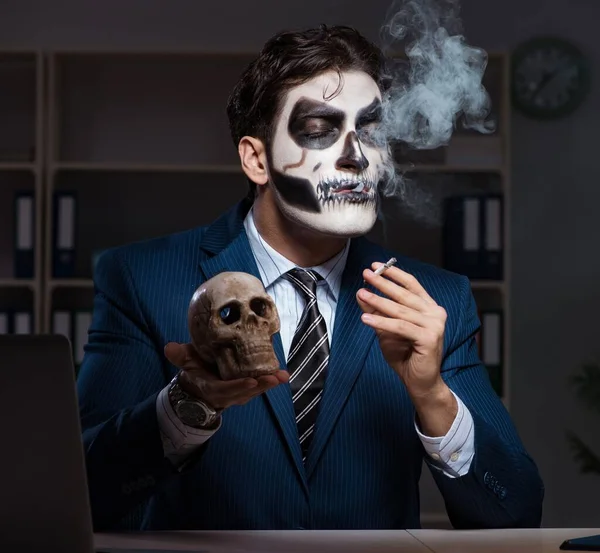 Zakenman met angstaanjagend gezichtsmasker die laat op kantoor werkt — Stockfoto