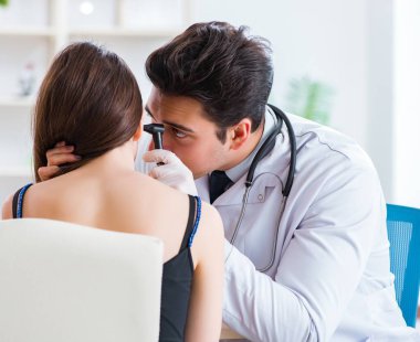 Doktor muayene sırasında hastaların kulaklarını kontrol ediyor.