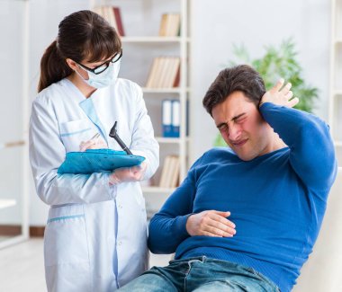 Doktor muayene sırasında hastaların kulaklarını kontrol ediyor.