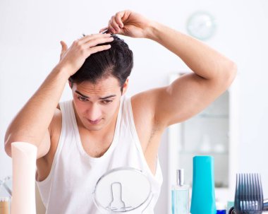 Genç yakışıklı adam aynaya bakıyor.