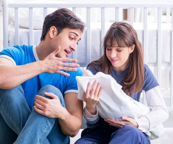 Padres jóvenes con su bebé recién nacido sentado en la alfombra — Foto de Stock