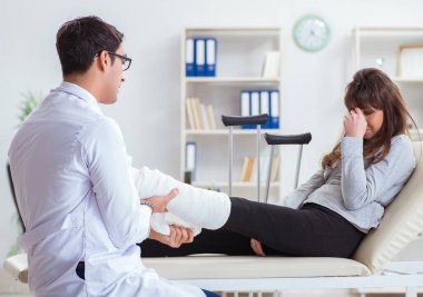 Kırık bacaklı bir hastayı muayene eden doktor.
