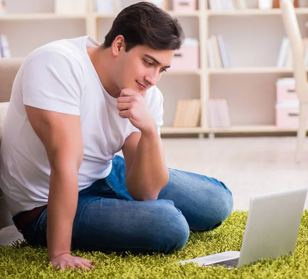 L'uomo che lavora su computer portatile a casa su pavimento di tappeto — Foto Stock