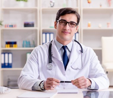 Genç doktor ofiste oturuyor.