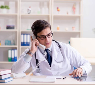 Genç doktor ofiste oturuyor.