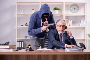 Genç gangster yaşlı yargıcı tehdit ediyor.