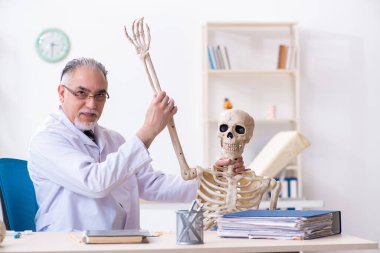 İskeleti olan yaşlı erkek doktor.