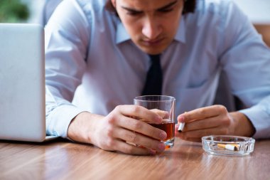 İş yerinde alkol ve sigara içen bir erkek işçi.