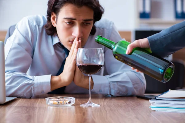 Mužský zaměstnanec pije alkohol a kouří cigarety na pracovišti — Stock fotografie